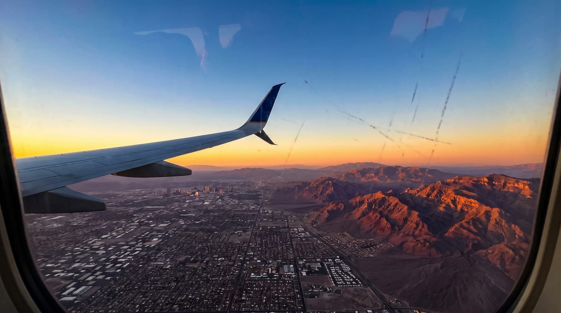 Airplane window view descending toward the Las Vegas valley at sunset